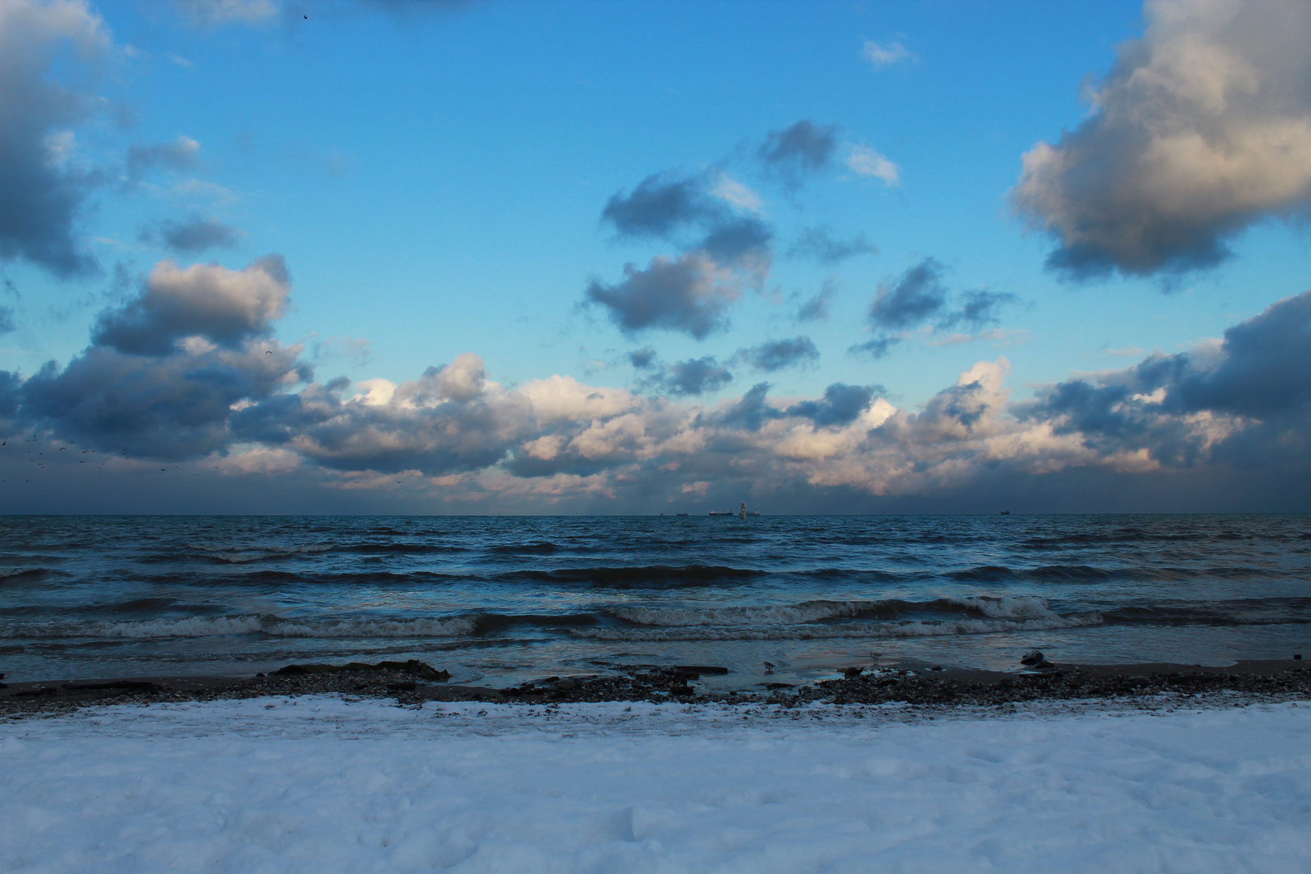 widok na chmury, dale na morzu i śnieg na plaży